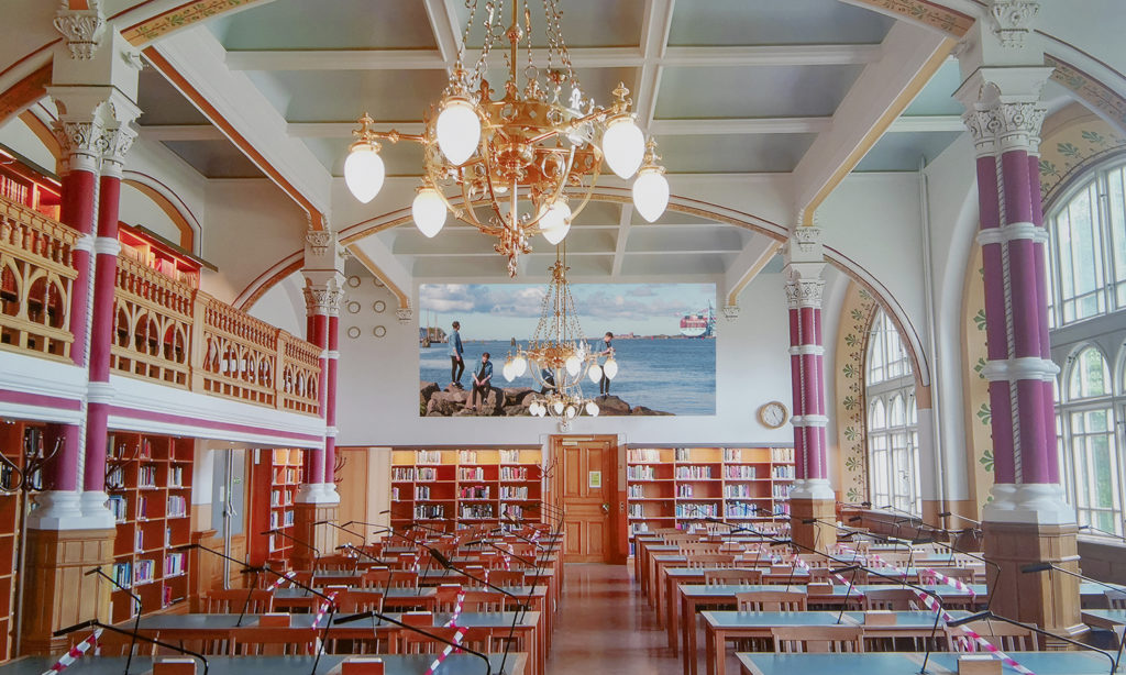 Visualiseringsbild av fotografiet när det hänger på kortsidan inne i Samhällsvetenskapliga bibliotekets pampiga läsesal.