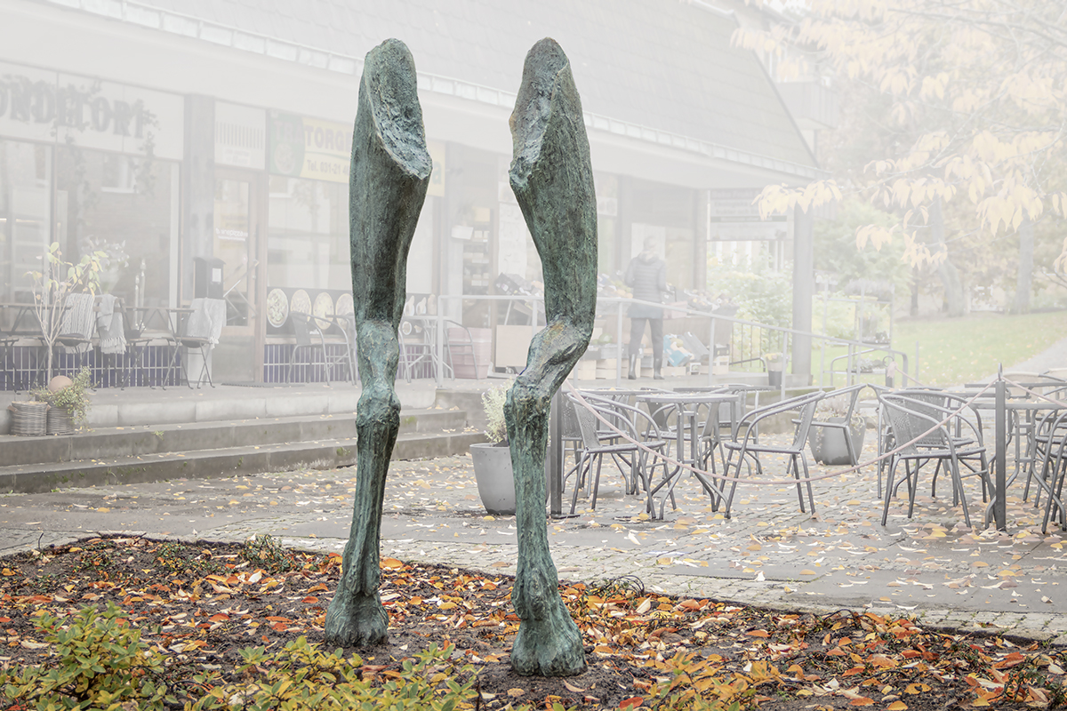 Två ben står i en rabatt. Benen har klövar som fötter som sedan glider över i människolår.