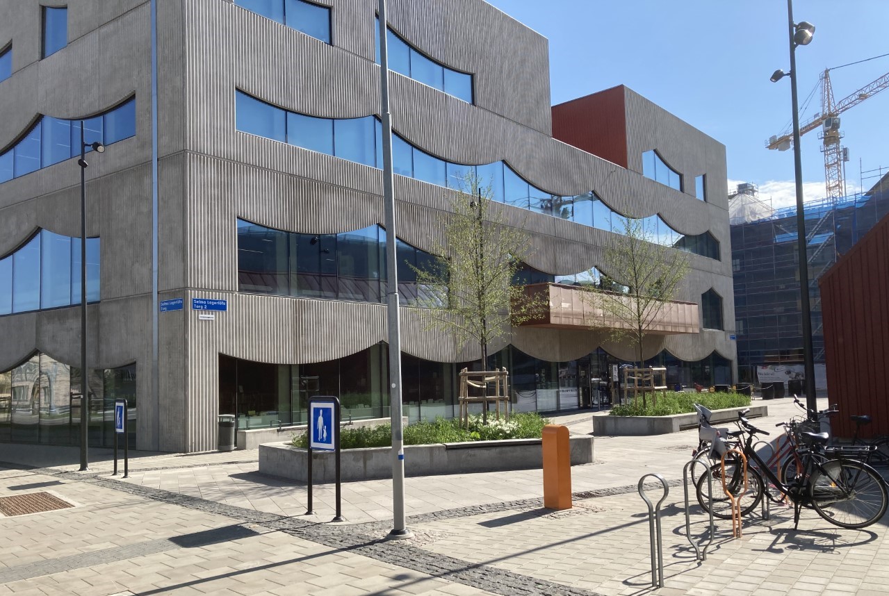 Selma Lagerlöfs Centers fasad pryds av ikoniska fönster i svängda former. Framför entrén syns två större rabatter.