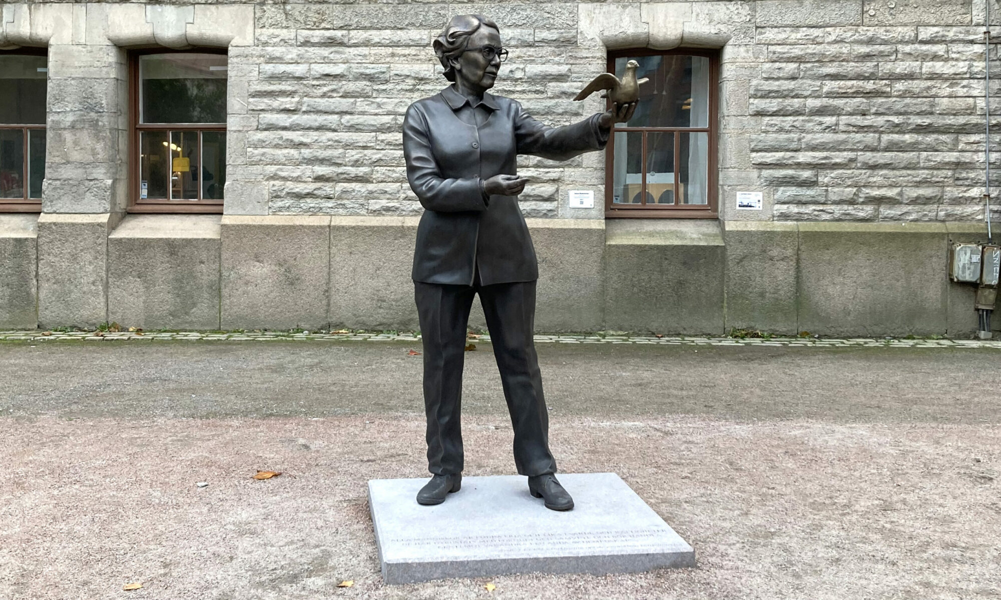 Skulptur av Ingrid Segerstedt Wiberg. Ena armen är utsträckt, och på den sitter en fredsduva som ser ut att vara redo att flyga iväg.