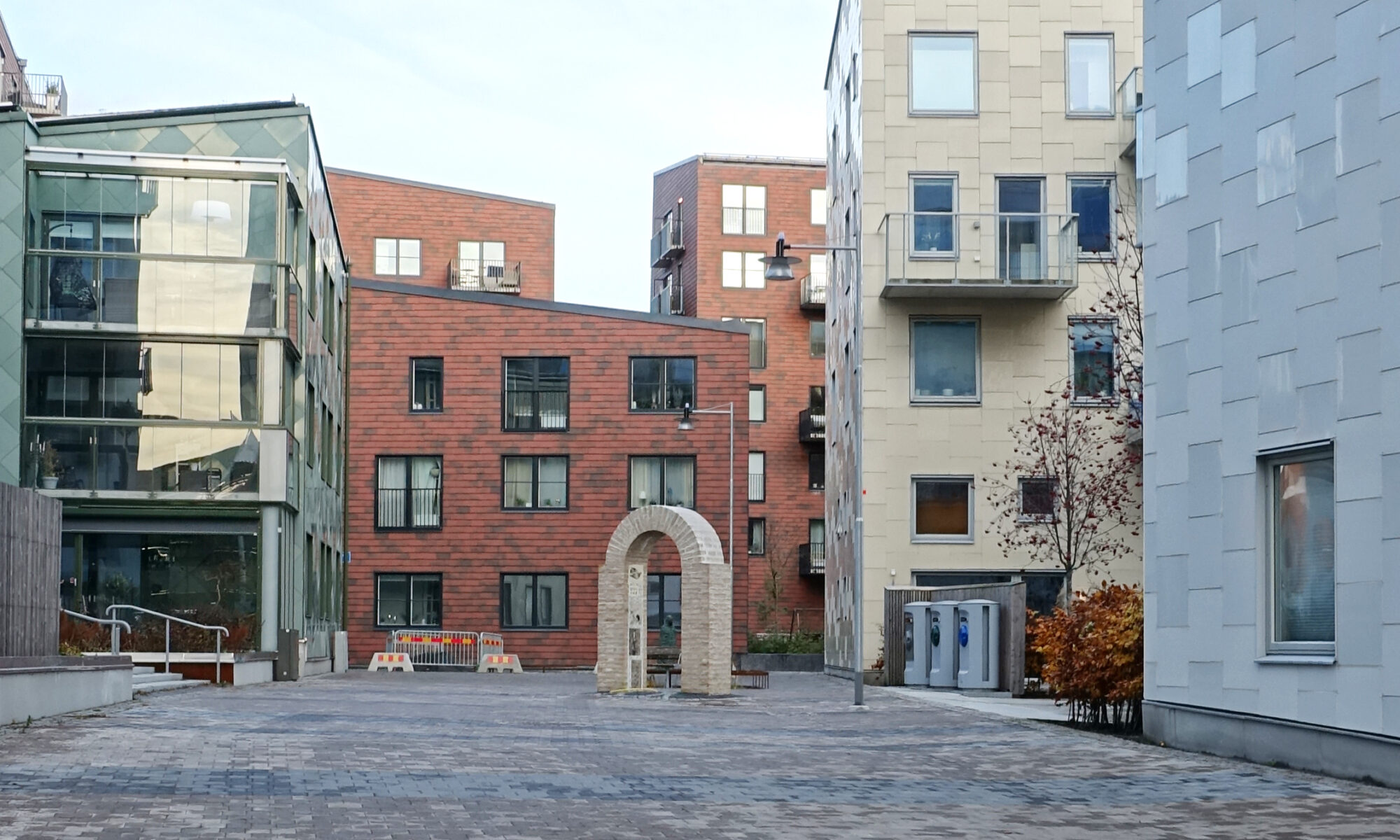 Ett murat portvalv med bostadshus i bakgrunden.