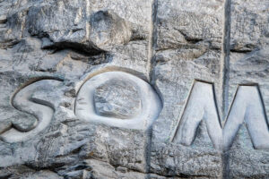 Närbild på ordet "som", som är infräst i bergväggen.