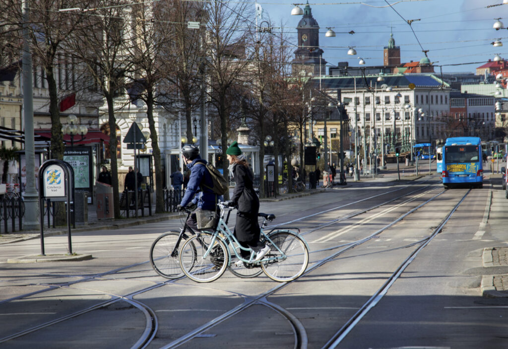Två cyklister cyklar över spårvagnsspåren på Avenyn