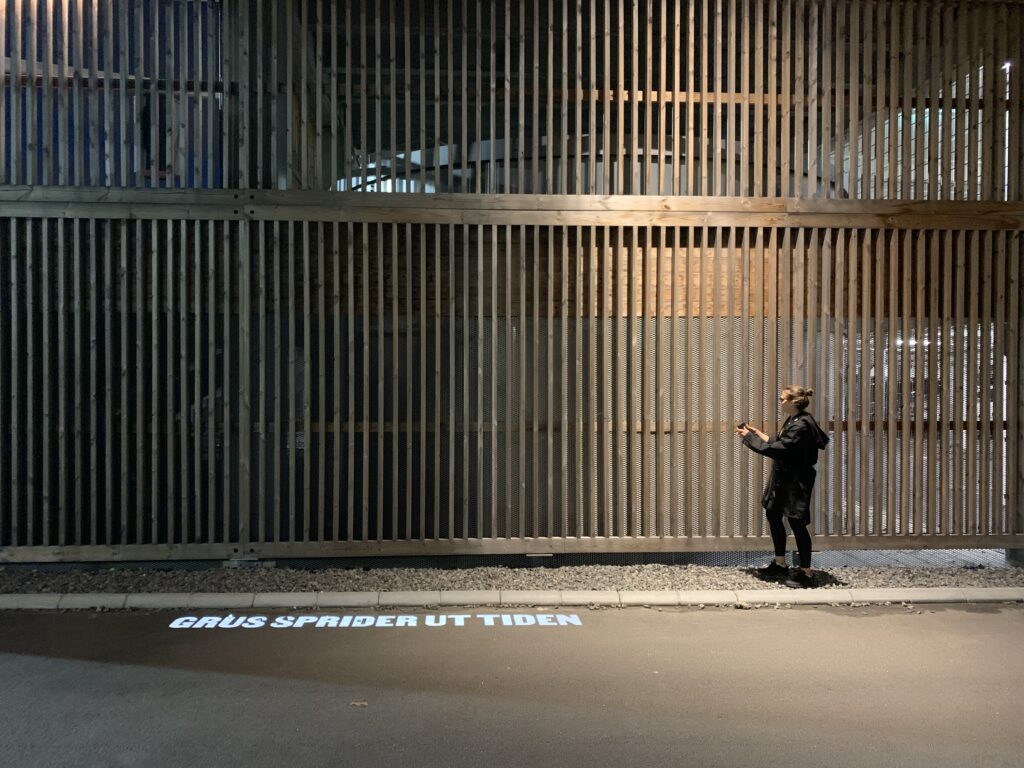 Texten Grus sprider ut tiden projiceras på asfalten med stora vita bokstäver