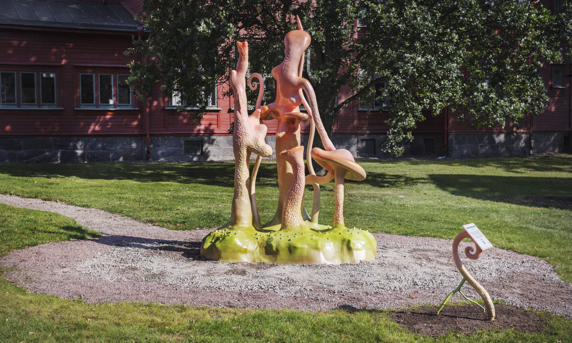 Ett foto av ett utsnitt från en rosa skulptur i olika organiska former som sträcker sig upp från marken.