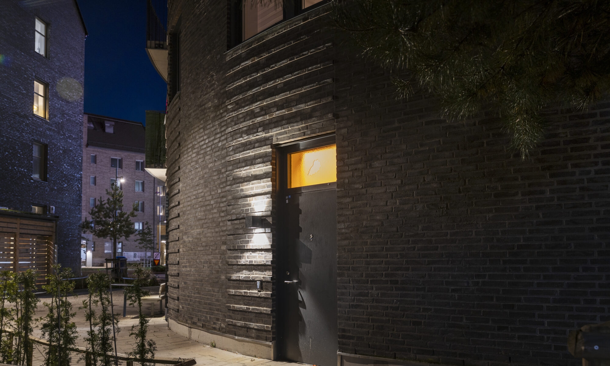 Ett foto av en ytterdörr med en sprucken ruta med orange ljus bakom och ett titthål där det syns ett blått sken.