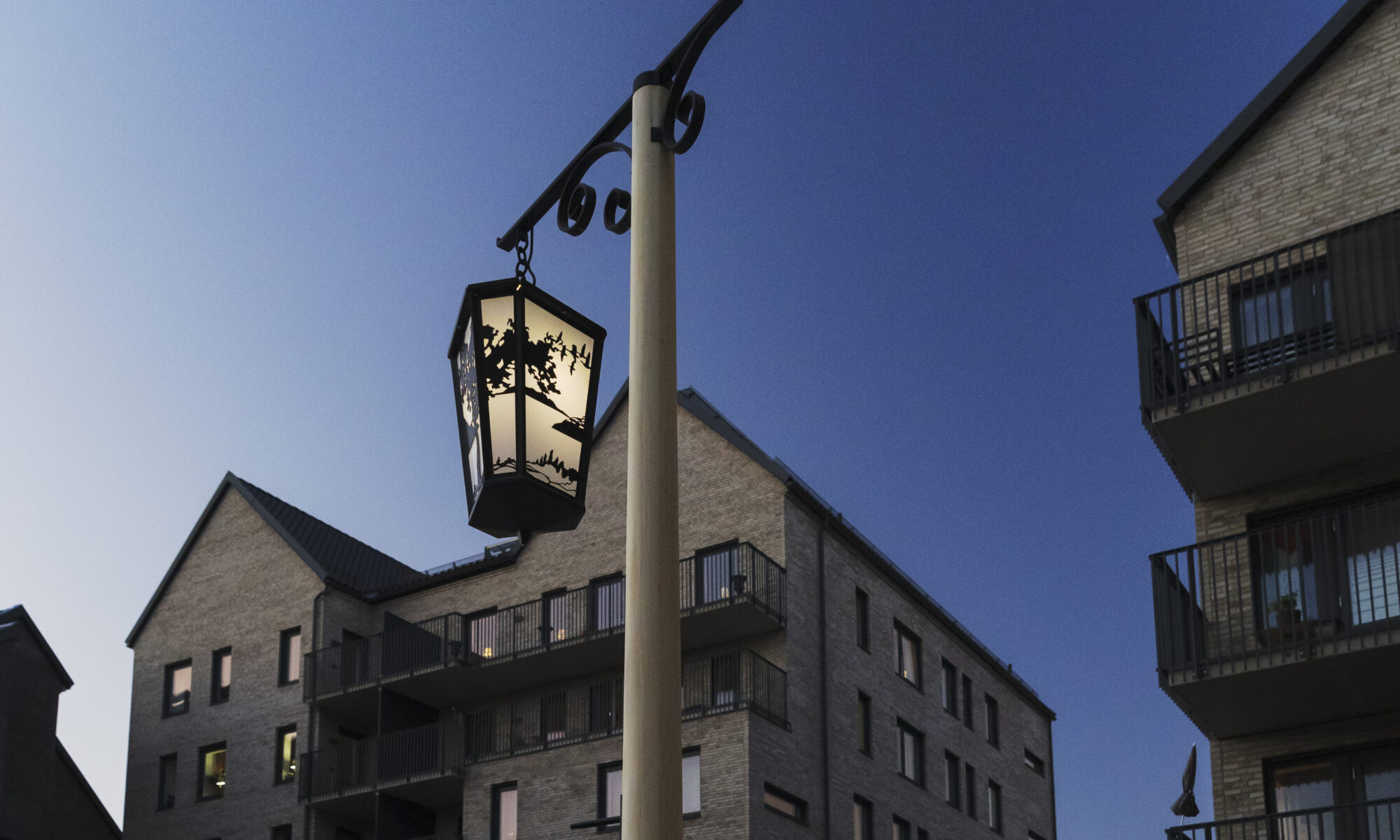 Ett foto av en lykta med siluettmotiv framför ett nybyggt hus.