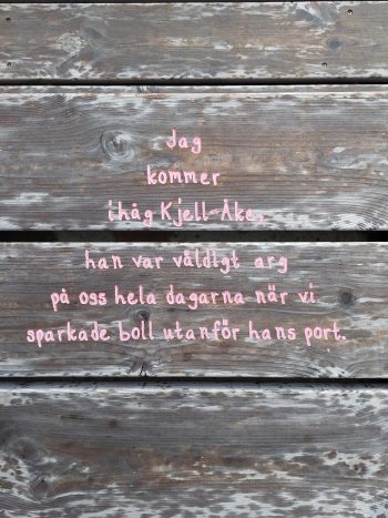 Del av konstverket Viskningar Garvad rosa text som lyder: "Jag kommer ihåg Kjell-Åke, han var väldigt arg på oss hela dagarna när vi sparkade boll utanför hans port".