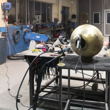 Urd, Skuld och Verdandi - nornornas port består av flera olika komponenter. Högst upp finns en guldskimrande boll. På bilden ser du när den skapas i verkstaden.